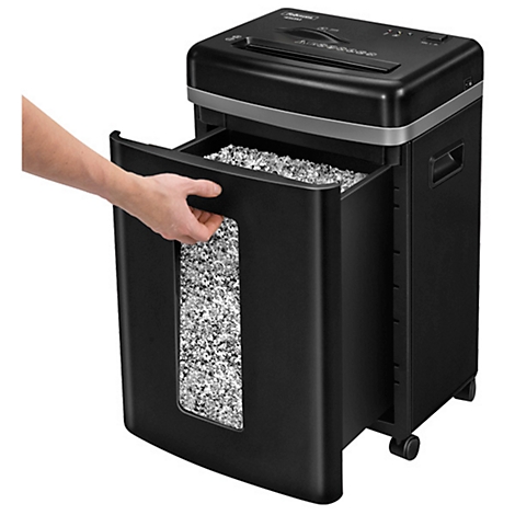 A black paper shredder with the collection container pulled out. A man's hand is emptying the container.