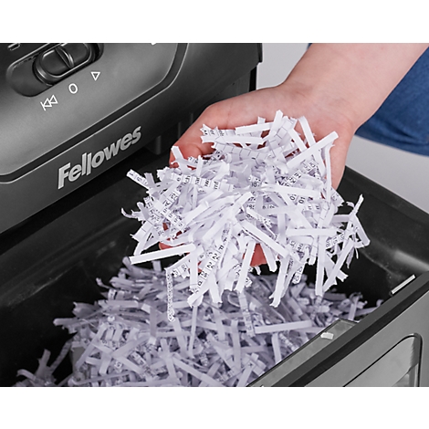 A hand holds shredded paper over a paper shredder. The inscription 'Fellowes' can be seen.