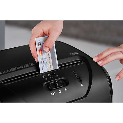 Hand inserting credit card into shredder. Logos and numbers are visible on the card.