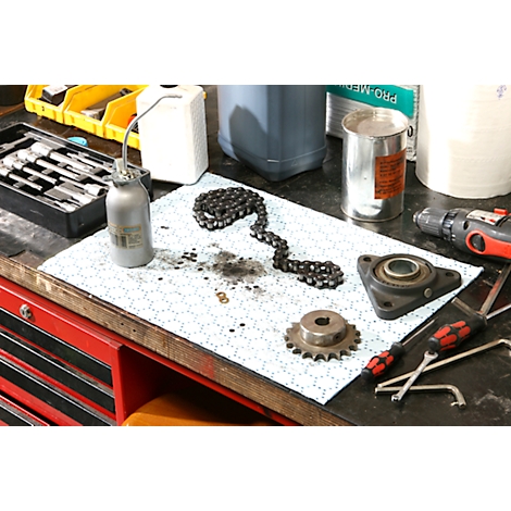 Une chaîne, un pignon, des outils et une burette d'huile reposent sur une table.