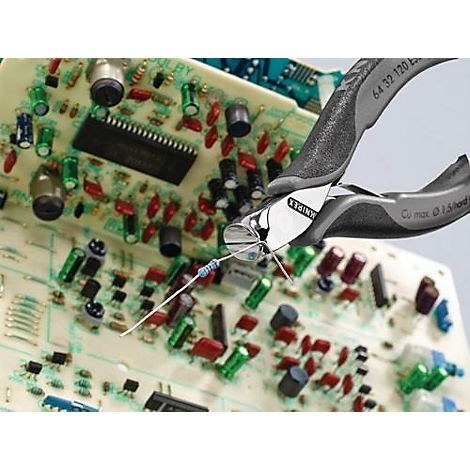 Une pince coupante coupe un fil sur une carte de circuit imprimé. Le fond montre des composants électroniques.