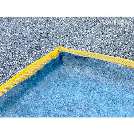 Hoek van een blauw zeil met een gele rand, op een grijze ondergrond.