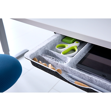 Offene Schublade unter einem Schreibtisch mit Filzeinsatz, gefüllt mit Büromaterial wie Schere, Stift und Tablet.