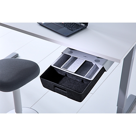 Eine offene, schwarze Filzschublade unter einem weißen Schreibtisch mit Laptop.