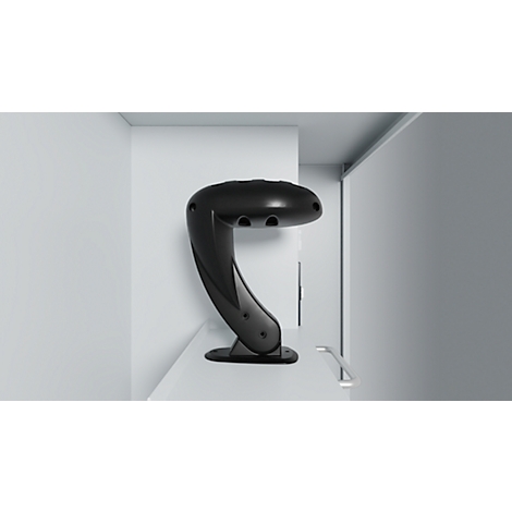 Black lamp in a white room. The lamp has a modern design with a curved shape.