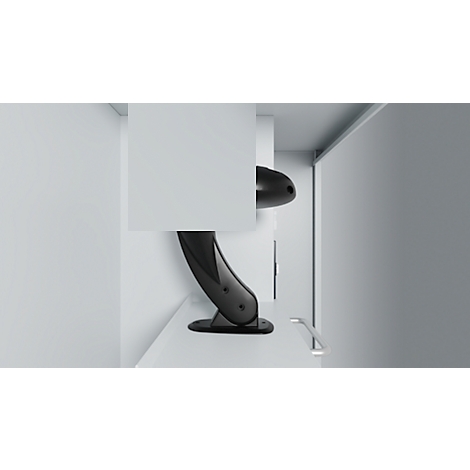 Black, futuristic lamp placed in a corner. It has a curved shape and stands on a white surface.