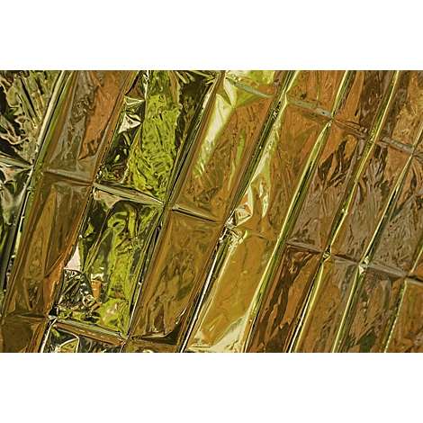 Close-up van een glanzende, gouden reddingsdeken met karakteristieke vouwpatronen en reflecties.