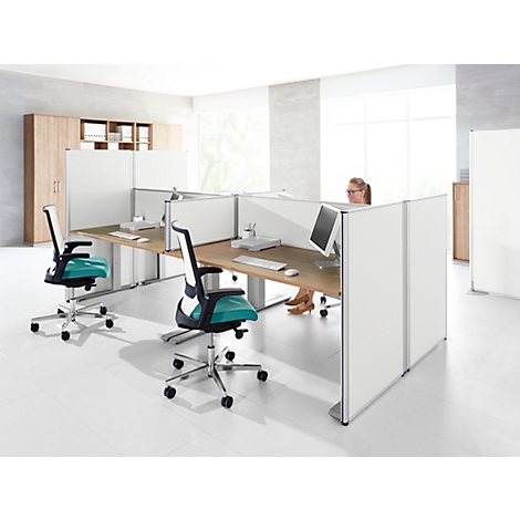 Office with multiple workstations. A woman sits at a desk, two office chairs with turquoise seats.