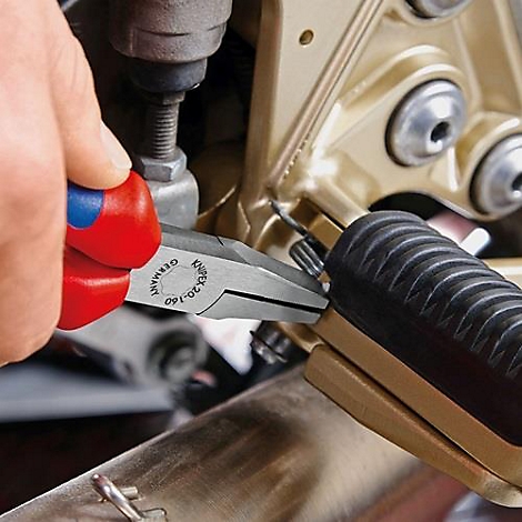 Person repairing motorcycle with pliers. Pliers with red and blue handle.