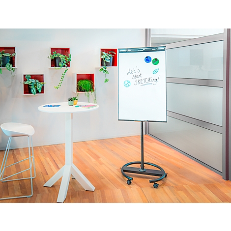 Un tableau de conférence dans un bureau moderne. Le tableau blanc dit "Let's start sketching!". Une table ronde, une chaise et une décoration murale.