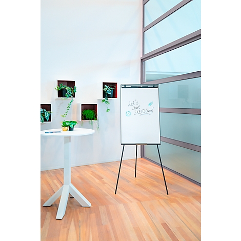 Un tableau blanc avec les mots "Let's start sketching !" est posé sur un sol en bois. Derrière, un mur blanc avec des plantes vertes.
