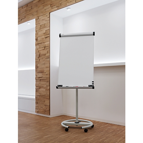 Een wit flip-overbord staat in een lichte kamer. De achtergrond is wit en ontworpen met een houten element en een houten vloer.