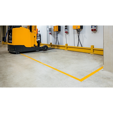 Yellow forklift in warehouse, yellow lines mark floor. Power boxes on wall.