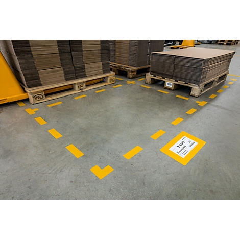 Yellow marking lines on concrete floor, pallets with cardboard, label.