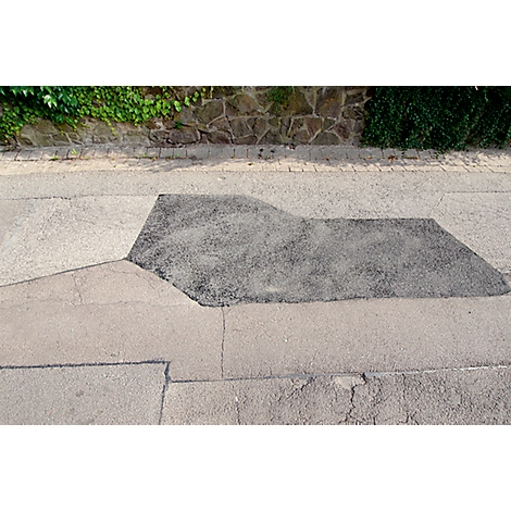 Patch of asphalt on a road, surrounded by gray paving. Top: wall with greenery. Top view.