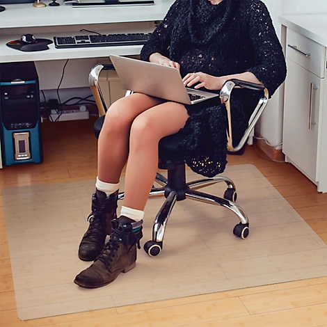 Vrouw die op een laptop werkt. Draagt een zwarte jurk, laarzen en witte sokken. Zittend in een bureaustoel, met een toetsenbord voor zich.