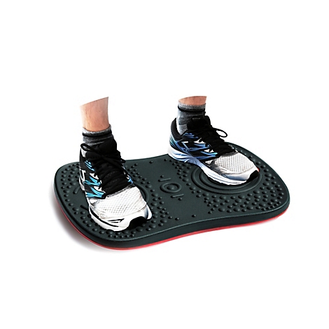 Zwei Füße in Turnschuhen stehen auf einem schwarzen Balance-Board. Das Board hat eine rote Kante und Noppen.