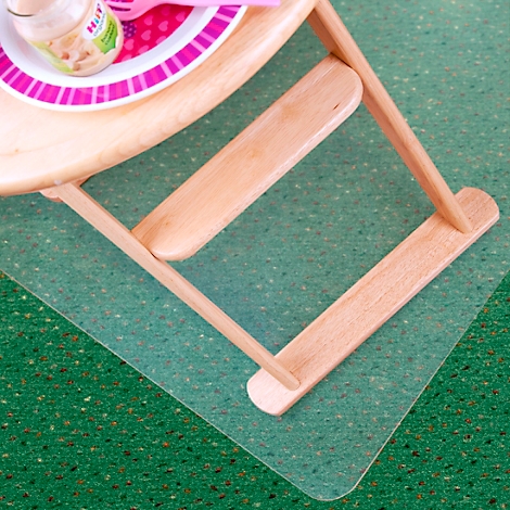 Detailopname van een houten kinderstoel met servies op een groen tapijt.