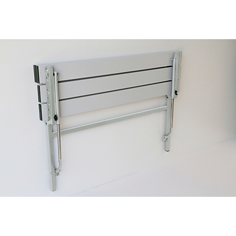 A gray, folded wall-mounted table with silver legs against a white wall.