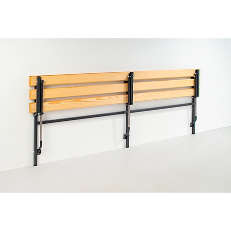 A wooden headboard with black metal legs stands in front of a white wall.