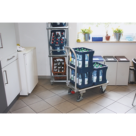 A serving cart with beverage crates in a room. Shelves and a window with plants can be seen in the background.