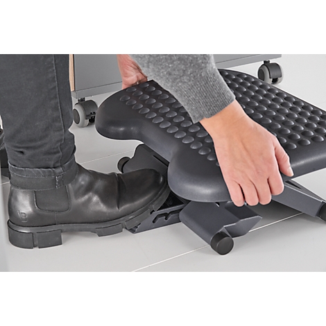 Person holding a black footrest, leg with shoe next to it.