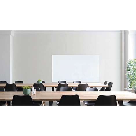 Conference room with wooden tables, black chairs and a blank whiteboard. Green foliage stands near the window.