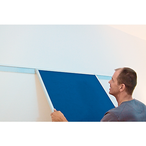 Man attaching a blue board to the wall.