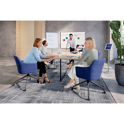 Conferentieruimte met meerdere mensen die aan tafel zitten. Notities staan op een whiteboard. Een man staat.