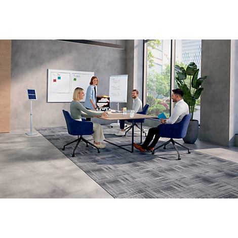Team vergadert aan tafel, er wordt gediscussieerd. Een flip-over en een whiteboard zijn op de achtergrond te zien.