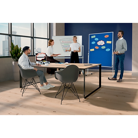 Vier mensen presenteren ideeën op een kantoor, ideeën staan op een bord en prikbord. Er liggen notities op tafel. Er staat een plant aan de muur.