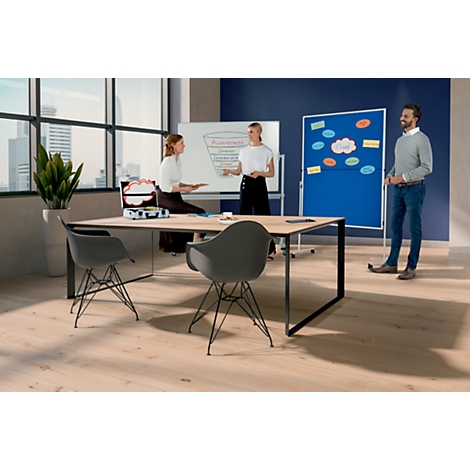 Drie mensen in een kantoor die brainstormen aan een tafel met twee stoelen. Op de achtergrond een whiteboard en een prikbord.