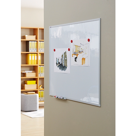 A white board with drawings and magnets on a wall. A shelf on the left, a beige wall on the right.