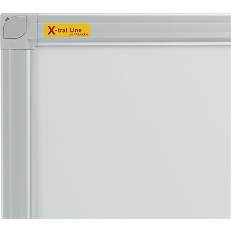 Sectie van een wit bord met een zilveren frame. Een hoek is zichtbaar linksboven. Een gele sticker leest "X-tra! Line by FRANKEN".