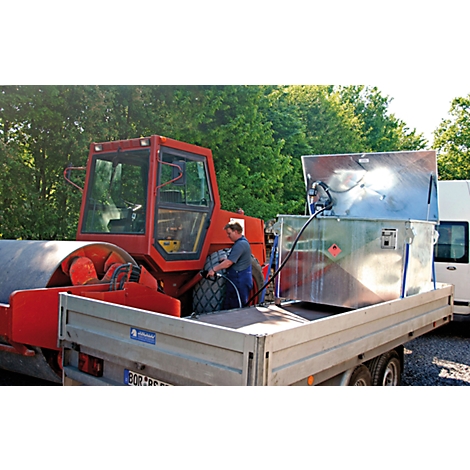 Man fueling a road roller. Tank and roller are on a trailer.