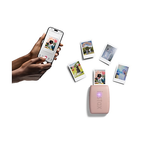 Person hält Smartphone mit Foto, daneben Fotos und ein rosa Drucker.