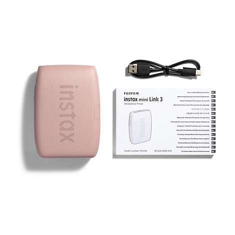 Rosa instax mini Link 3 Drucker, USB-Kabel und Handbücher. Das Gerät hat Rillen und ist mit dem instax-Logo versehen.