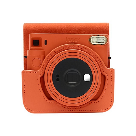Eine orangefarbene Instax-Sofortbildkamera in einer passenden Schutzhülle, vor weißem Hintergrund. Der Objektivring ist schwarz.