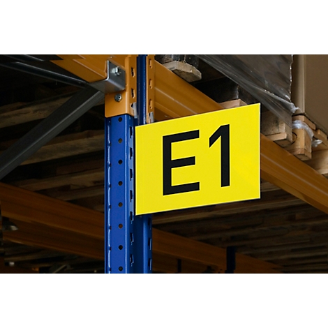 Gelbes Schild mit der Aufschrift "GATE E1" an einer Lagerhalle. Die Szene wirkt industriell.