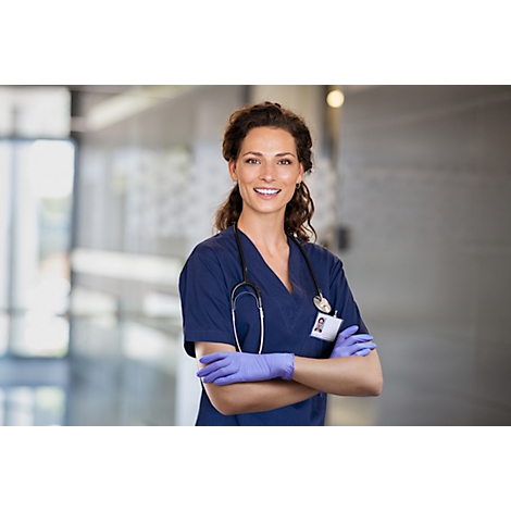 Infirmière souriante, les bras croisés, en uniforme bleu, gants et stéthoscope.