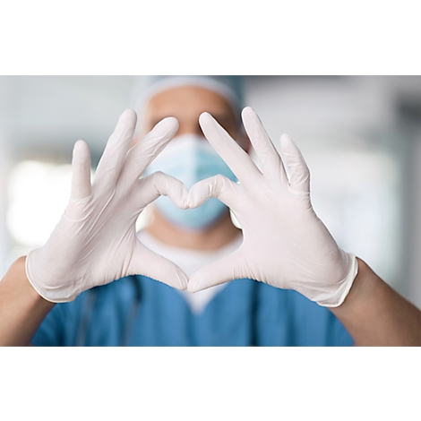 Une personne en tenue médicale forme un cœur avec ses mains gantées. Le visage et les vêtements chirurgicaux sont indiqués en arrière-plan.