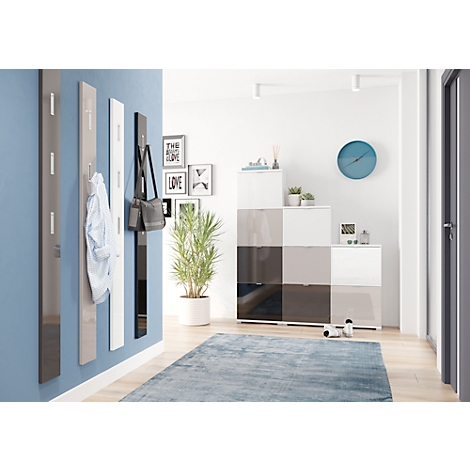 Gang met kapstok, schoenenkast, vloerkleed en klok. Hangers, tassen en een overhemd hangen aan de blauwe muur.