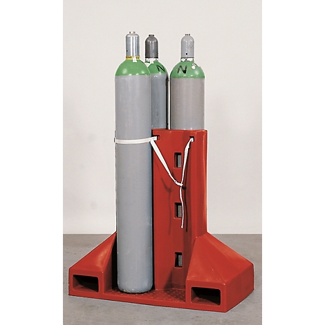Three gas cylinders stand on a red holder. Two are gray, one is green, and secured with a white band.
