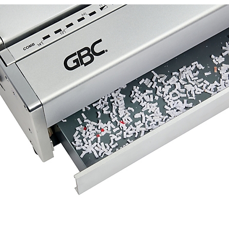 Gros plan d'une déchiqueteuse de papier argentée avec le bac de collecte sorti, rempli de morceaux de papier déchiqueté.