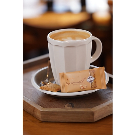 Eine cremige Tasse Kaffee in einer geriffelten Tasse mit einer Karamellwaffel auf einem Holztablett.