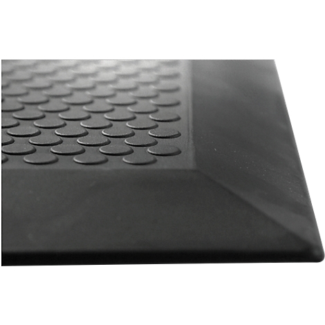 Close-up of a black rubber mat with raised round studs and beveled edges.