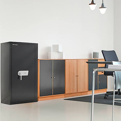 Schwarzer Tresor mit silbernem Griff in einem Büro. Im Hintergrund Schränke und Schreibtisch.