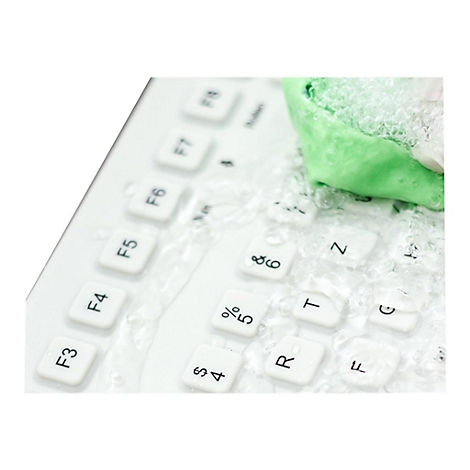 Eine weiße Tastatur wird mit einem grünen Tuch und viel Schaum gereinigt.