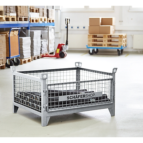 Graue Gitterbox mit schwarzem Inhalt, vor einem Lager. Auf der Box steht „SCHÄFERSHOP“.