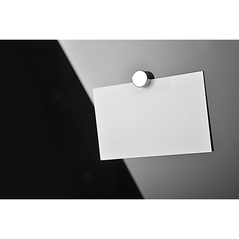 A white sheet of paper attached to a gray surface with a magnet, in front of a black background.